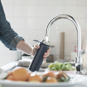 person filling up water bottle from tap
